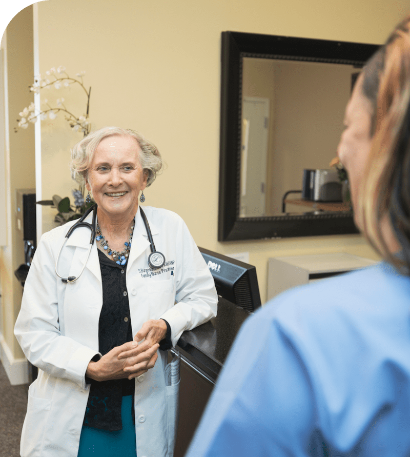 A nurse smiling while talking to a patient.